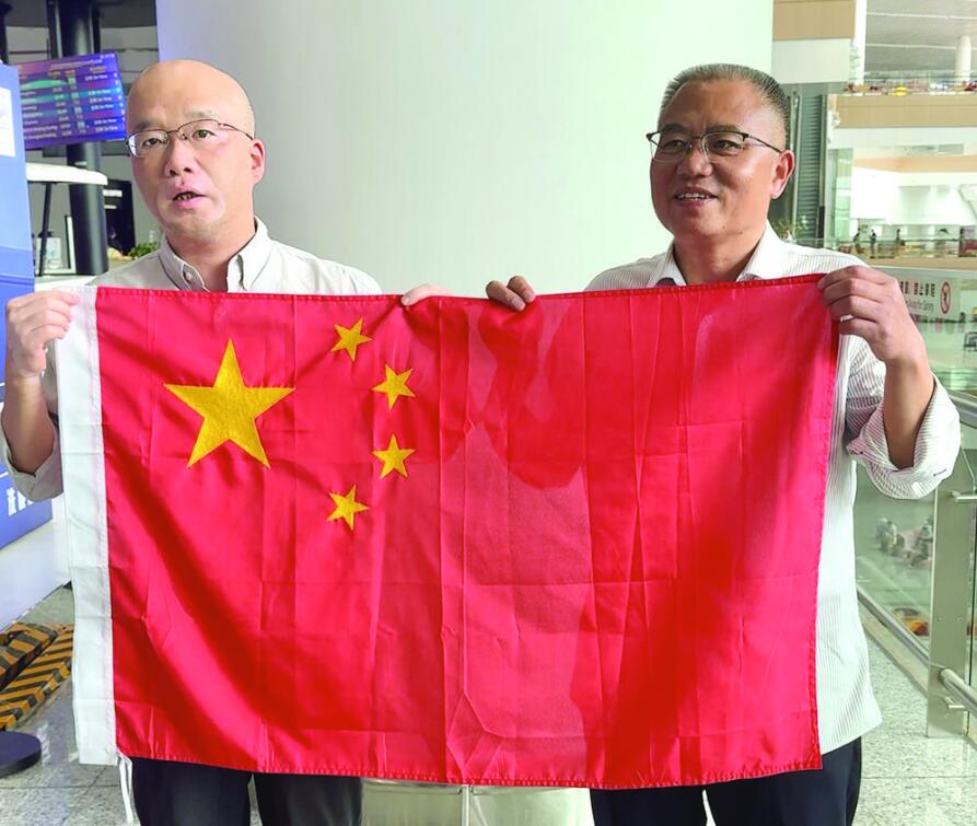 苏平(右一)、王虎炤展示珍贵的纪念品——湘绣五星红旗 记者 蒋欢 摄.jpg